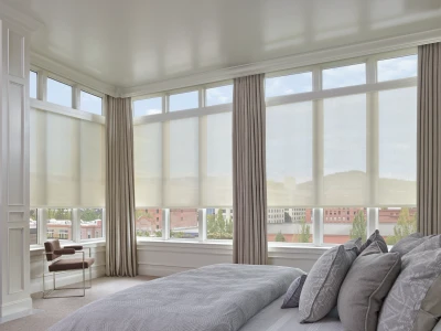 Layered window treatments — neutral drapery panels framing solar roller shades on a bedroom window